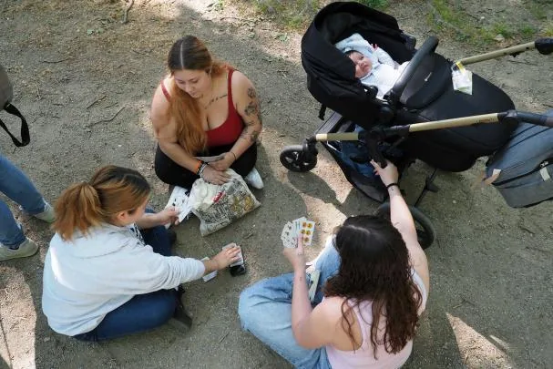 Three young people from Barcelona and Manresa play cards to pass the time; one of them was accompanied by her two-month-old baby at the casting.