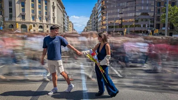 Una pareja cruza paseo de Gràcia/Aragó ajena a la multitud que transita por este punto del Eixample