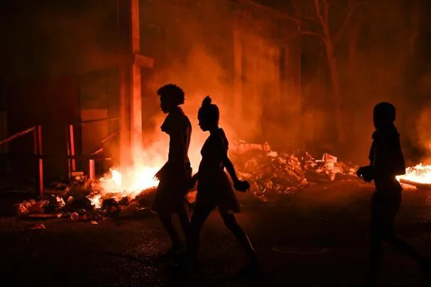 Young Cubans walk past a bonfire lit during Thursday's protests in the Lawton neighborhood of Havana.