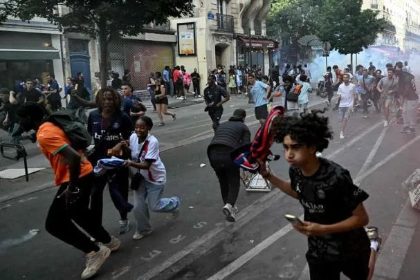 A group of PSG supporters runs to take cover from the tear gas launched by the riot police
