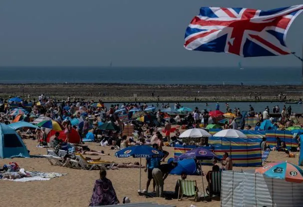The flag leaves no doubt about the setting. That photo of a crowded British beach in May is historic