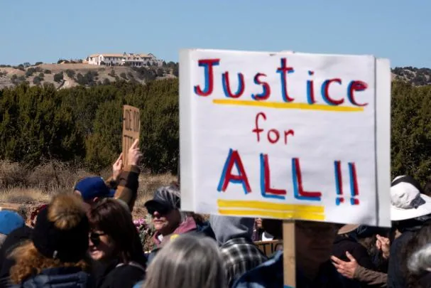 Jeffrey Epstein and his former property, Zorro Ranch, appear behind a protest banner that says “Justice for all” during International Women's Day near Stanley.