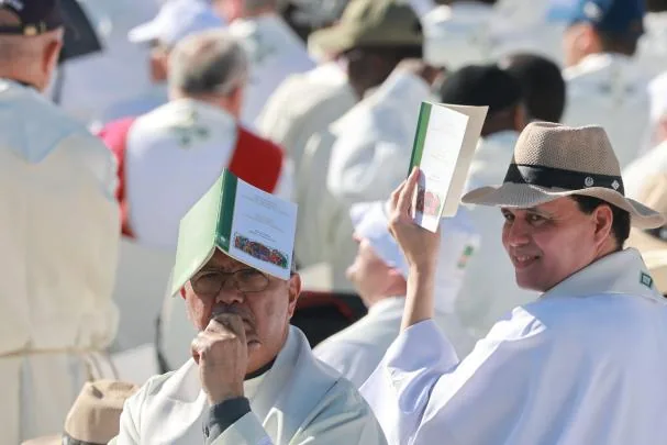 A priest protects himself from the sun during the Corpus Christi Mass