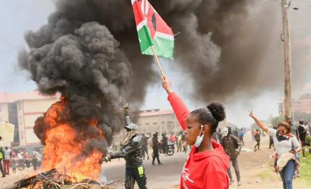 A young woman raises a Kenyan flag in Monday's protests against the U.S. Ebola quarantine center 