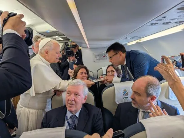 The Pope receives during the flight to Spain the book 'Leo XIV. A Pope for turbulent times', published by La Vanguardia, from the hands of the Rome correspondent Francesco Olivo
