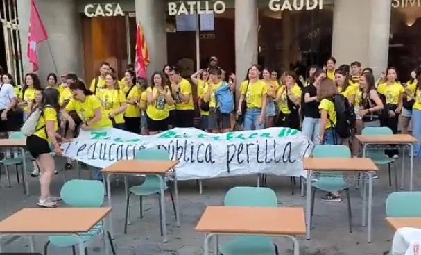 Several teachers hold up a banner in front of Casa Batlló.
