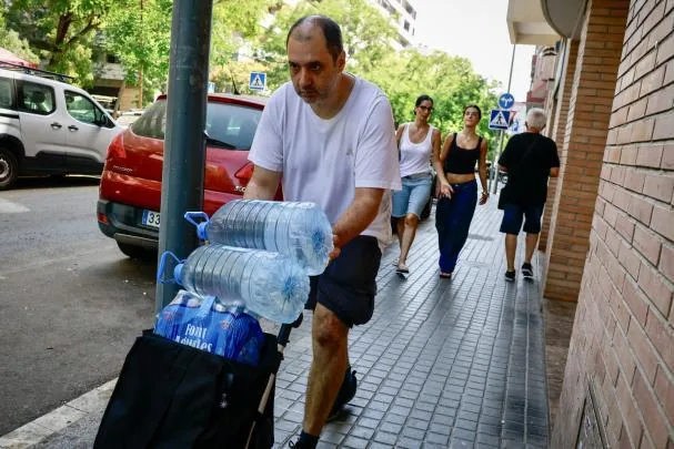 A man carries liters of water to cope with the high temperatures