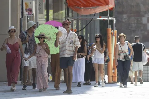 Several tourists protect themselves from the heat in the center of Barcelona, where temperatures exceeded 40 ºC last week