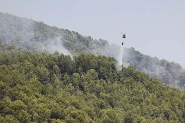 A helicopter drops water around Artana (Castellón), one of the municipalities affected by the fire declared last Saturday in La Vall d'Uixó (Castellón), which remains uncontrolled