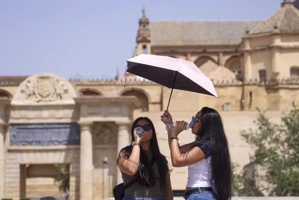 Varias turistas se protegen con paraguas mientras se refrescan ante las altas temperaturas en Córdoba