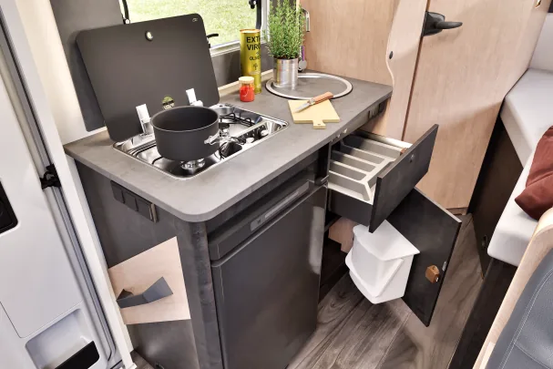 The kitchen is complete, with several burners, sink, fridge, and storage area 