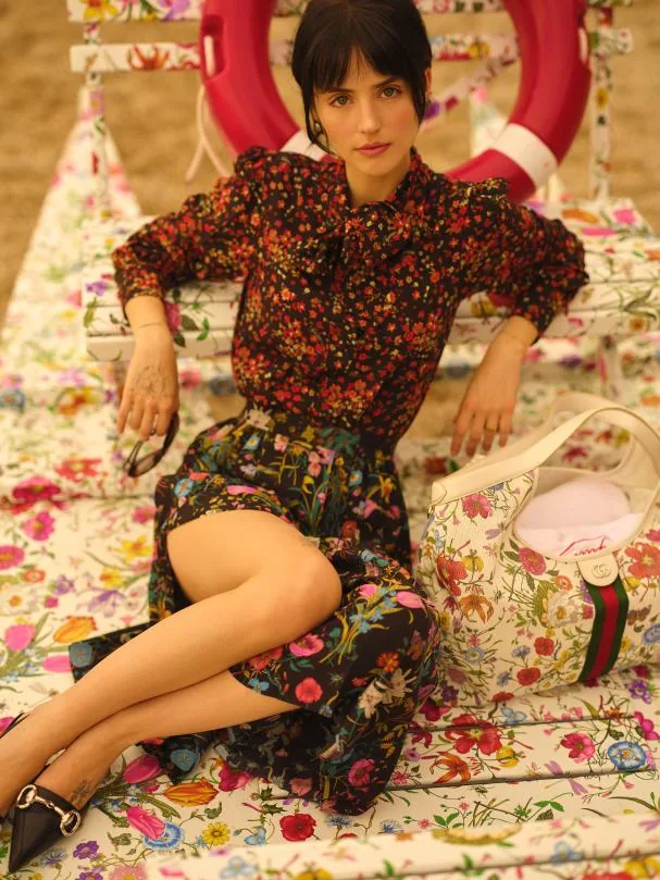 Pleated skirt and blouse with bow from the Gucci Montecarlo collection; Giglio Flora bag, Gucci jewelry and Kering Eyewear glasses