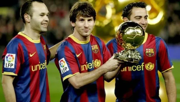 Iniesta and Xavi alongside Messi, in the center, showing the Ballon d'Or.