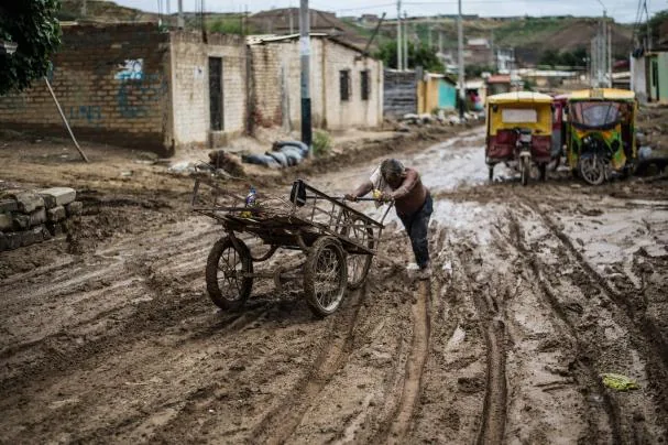 A local resident pushes his cart through the mud after floods caused by “El Niño,” in the province of Paita, in Piura, northern Peru.