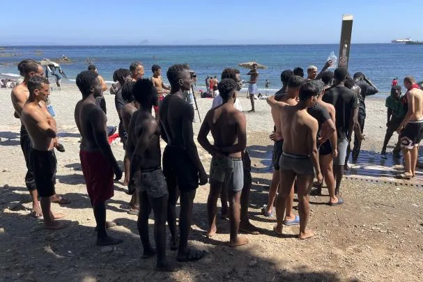 Young immigrants who sleep on the street queue to shower at Trampolín beach, after entering Ceuta last Thursday. EFE/ Reduan