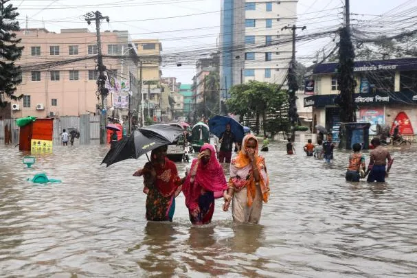 People walk through a flooded street after heavy rains in Chittagong on July 8, 2026.(Photo by AFP)