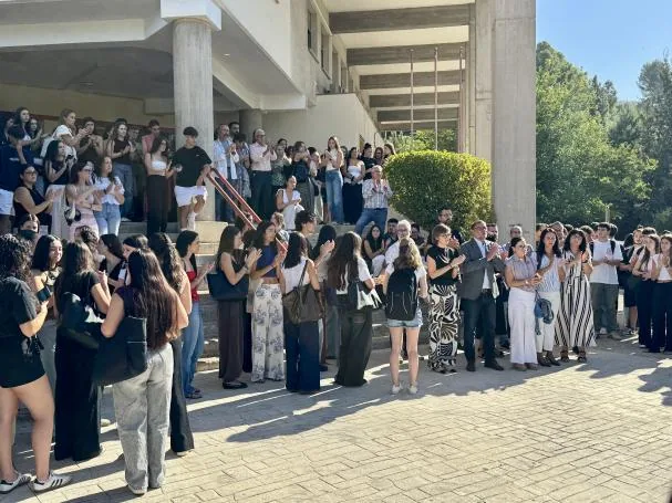 Claudia's classmates join the minute of silence in front of the Faculty door.