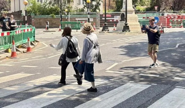 Two tourists emulate the Beatles on Abbey Road, in London