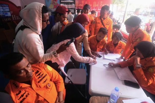 People look for the names of their relatives on a passenger list after a ferry capsized due to bad weather in the Java Sea.